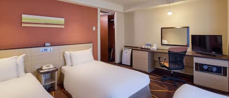 Habitación de hotel con dos camas, un escritorio con computadora, televisor y minibar.