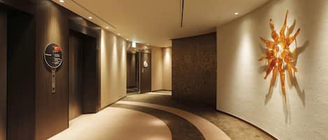 Un corredor moderno de hotel con un diseño de alfombra curva, un adorno en la pared y un cartel que indica los servicios.