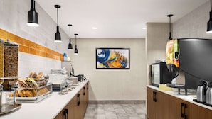 A modern kitchen with a white countertop, black pendant lights, a coffee machine, and a large painting on the wall. - La Quinta Inn Lexington/Horse Park (Lexington)