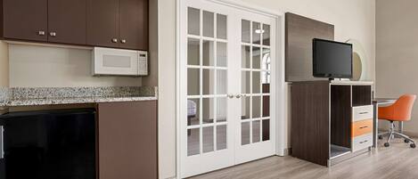 A modern kitchen with brown cabinets, a microwave, and a built-in refrigerator.