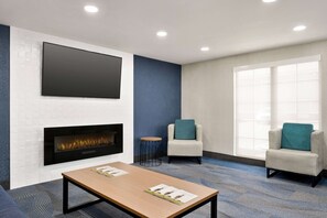 A modern lounge area with a flat-screen TV, a fireplace, two armchairs, and a coffee table. - La Quinta Inn Lexington/Horse Park (Lexington)