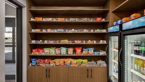A snack display with various packaged snacks and a refrigerated section with beverages. - La Quinta Inn Lexington/Horse Park (Lexington)