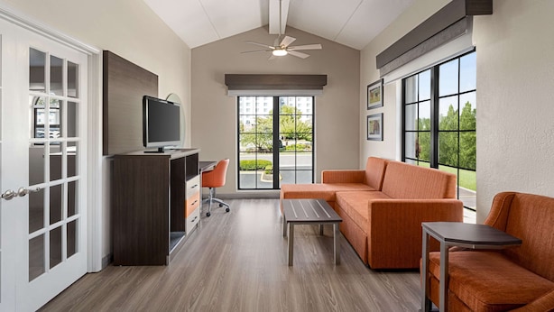 A modern living room with a sofa, a small table, a TV on a stand, and a desk with a chair. - La Quinta Inn Lexington/Horse Park (Lexington)