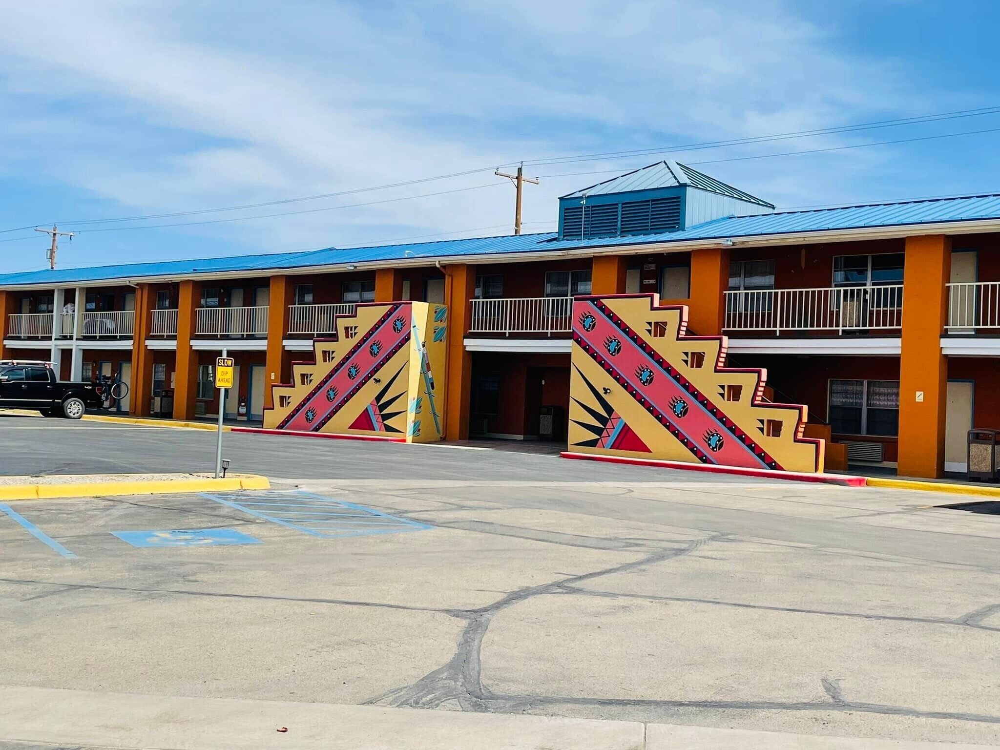 Motel amb teulada blava i parets taronja, que destaca per una rampa amb dibuixos en zig-zag.