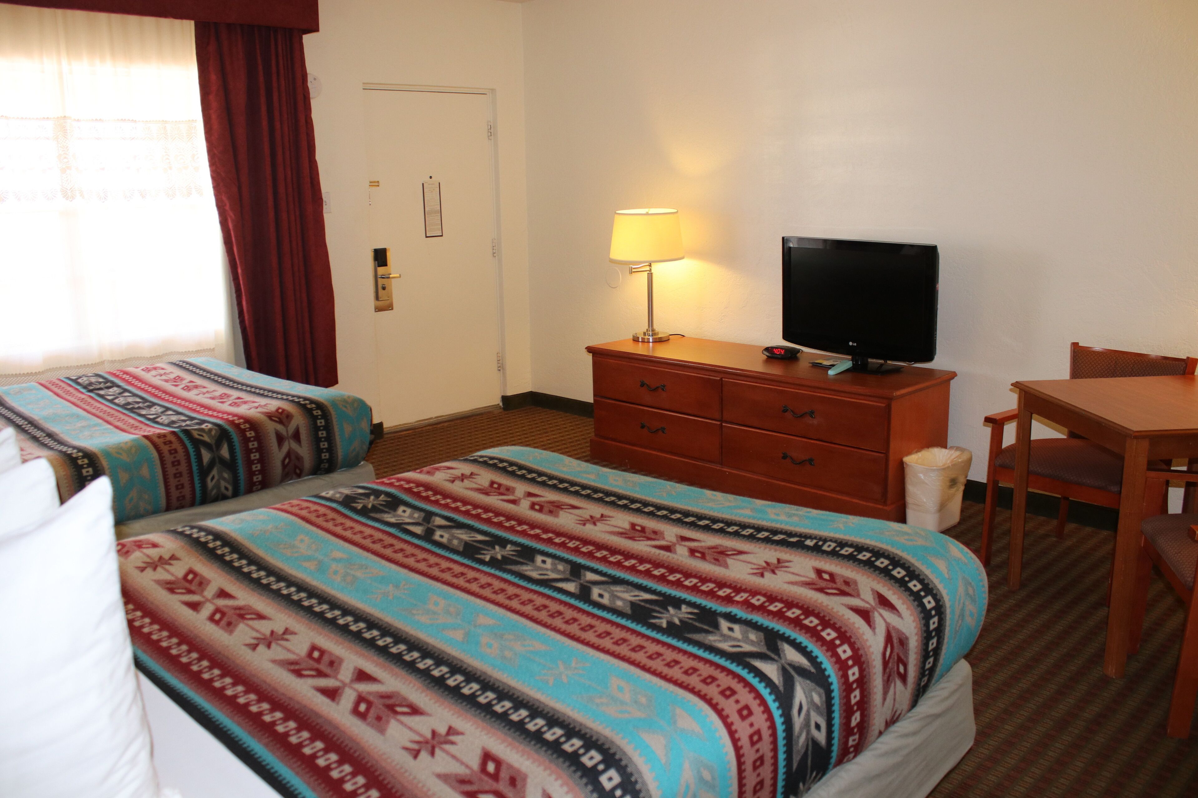 A hotel room with two beds, a television, a desk, and a chair.