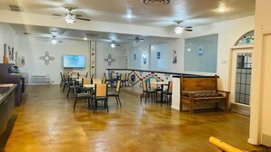 A spacious indoor area with multiple tables and chairs, ceiling fans, and a bar area. - The Classic Desert Aire Hotel (Alamogordo)