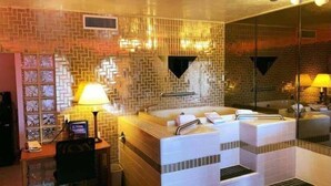 A bathroom with a large mirror, a bathtub, and a sink. - The Classic Desert Aire Hotel (Alamogordo)