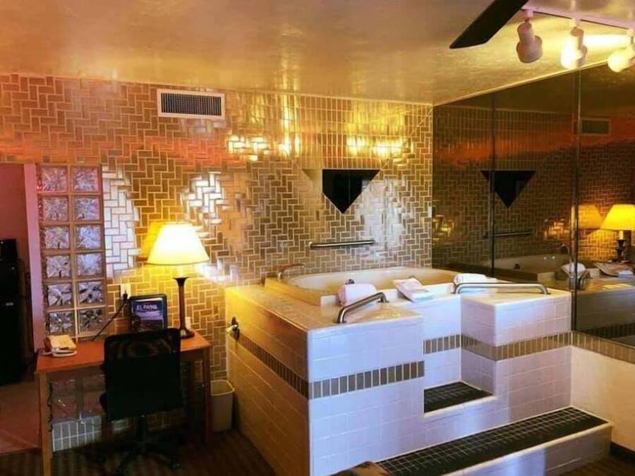 Un baño con un espejo grande, una bañera y un lavamanos.