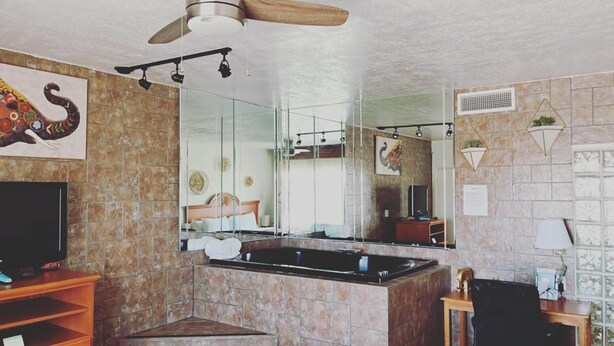 A modern kitchen with a central island, a ceiling fan, and a large mirror reflecting the room. - The Classic Desert Aire Hotel (Alamogordo)
