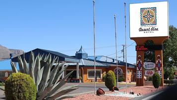 Un hôtel Desert Aire, reconnaissable à son enseigne bien visible, à son bâtiment bleu doté d’un toit en pente et à un grand agave placé au premier plan.