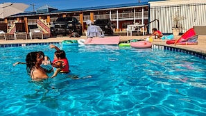 Piscina con juguetes inflables y una zona cubierta con sillas.