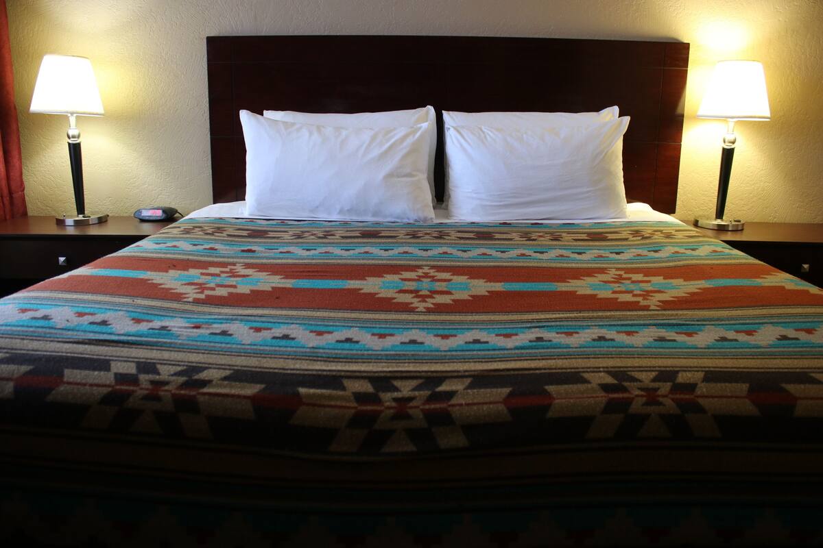 Un lit avec une couvre-lit à motifs, deux oreillers blancs et deux lampes de chevet.
