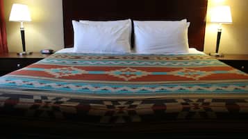 Una cama con colcha estampada, dos almohadas blancas y dos lámparas de noche.