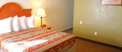 Habitación de hotel con cama, mesita de noche, lámpara y un cuadro en la pared.