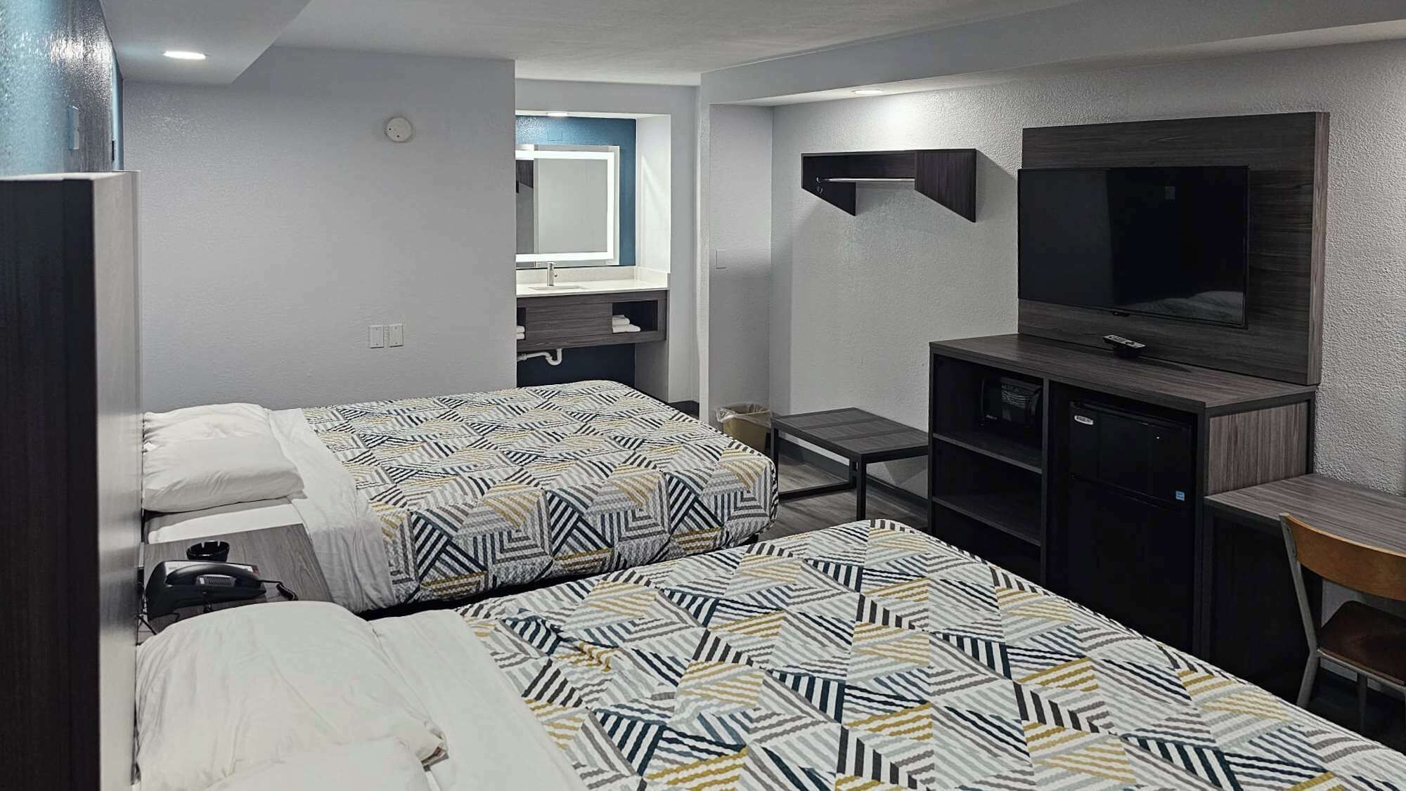 Une chambre d’hôtel avec deux lits, une télévision, un bureau et un miroir.