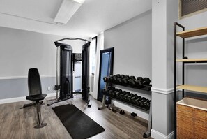 A home gym with a weight bench, a squat rack, and a rack of dumbbells. - Ramada by Wyndham Jacksonville I-95 by Butler Blvd (Jacksonville)