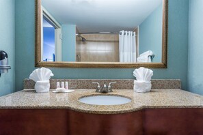 A bathroom with a large mirror, two sinks, and a shower. - Ramada by Wyndham Jacksonville I-95 by Butler Blvd (Jacksonville)