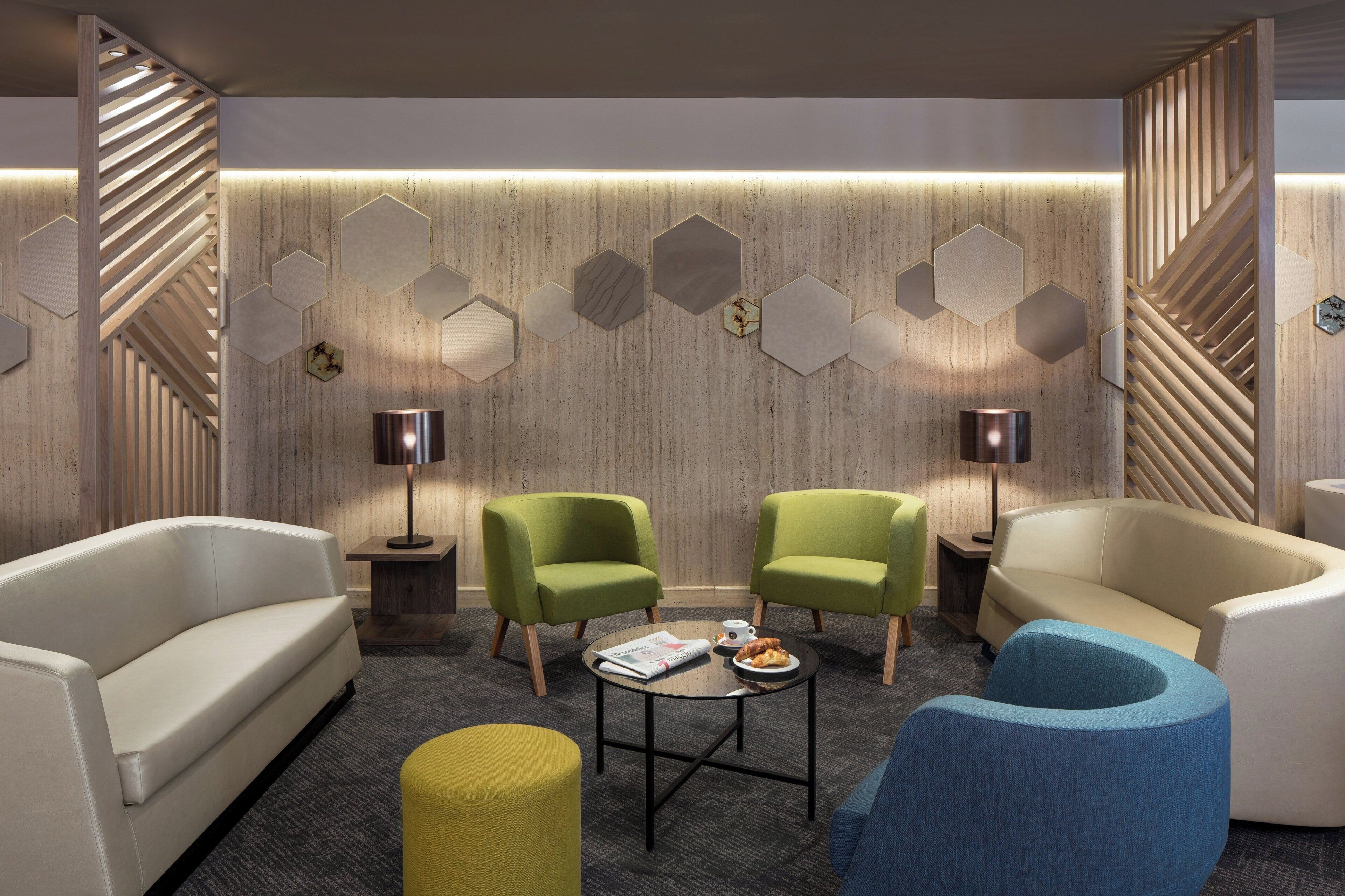 Een moderne zithoek met een bank, twee fauteuils, een salontafel en decoratieve wandpanelen.