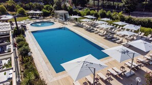 A large rectangular pool with a circular hot tub, surrounded by lounge chairs and umbrellas. - Holiday Inn Rome- Eur Parco Dei Medici by IHG (Rome)