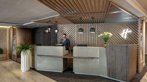 A modern reception area with a wooden ceiling, a reception desk, and a potted plant. - Holiday Inn Rome- Eur Parco Dei Medici by IHG (Rome)