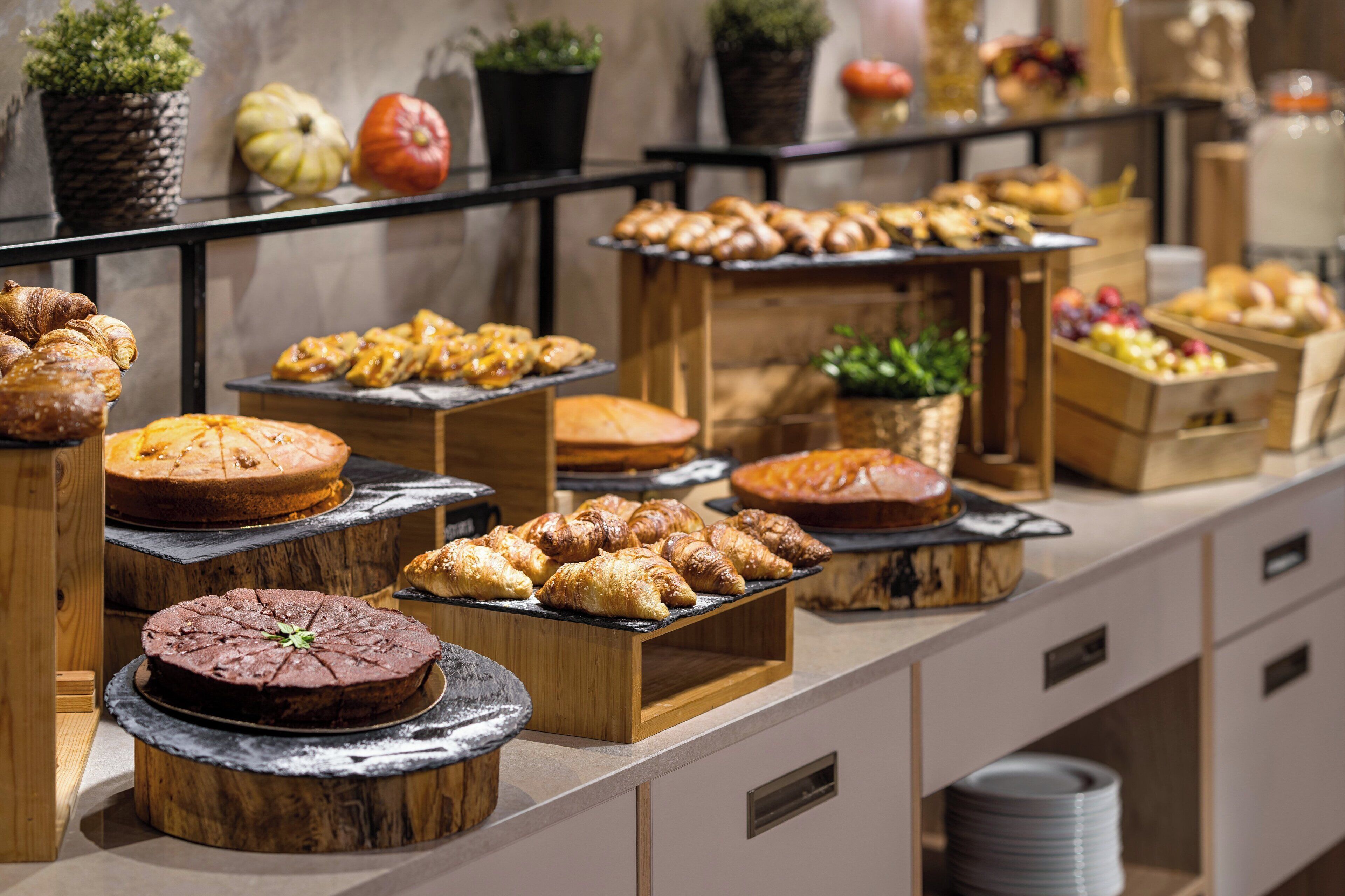 A buffet with various baked goods and pastries displayed on wooden stands and trays.