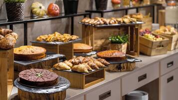 A buffet with various baked goods and pastries displayed on wooden stands and trays.