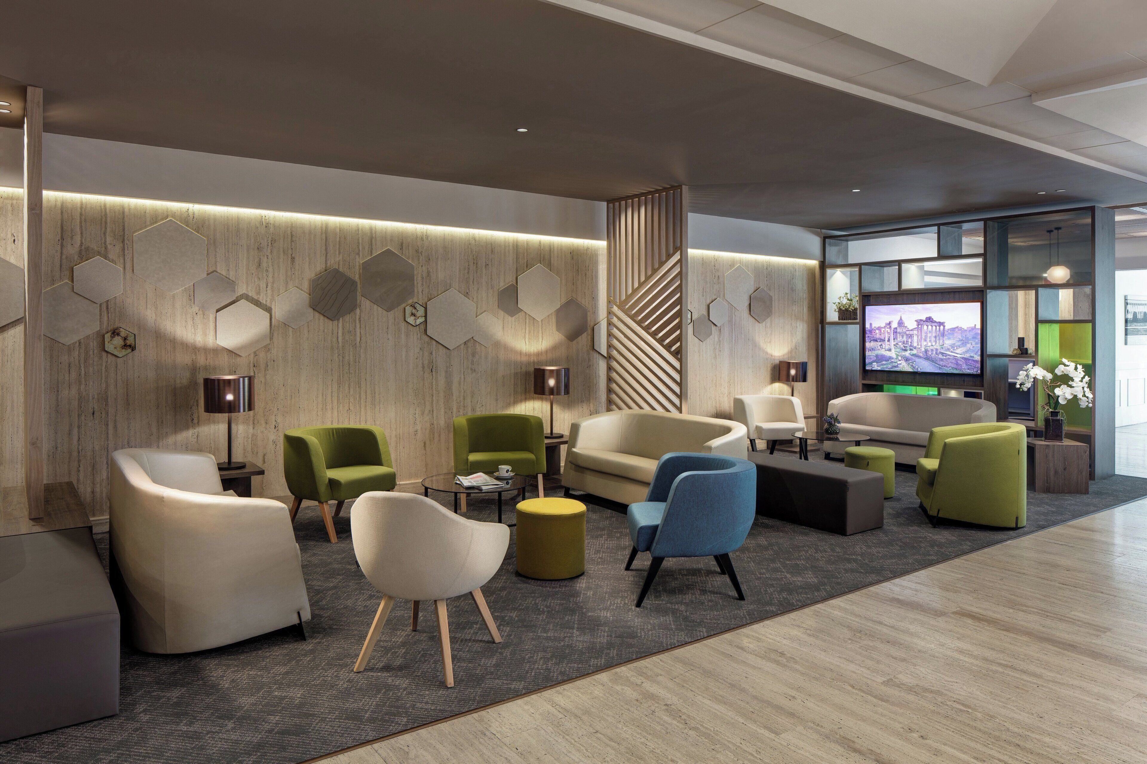 A modern lounge area with seating arrangements, a coffee table, and a television screen displaying a cityscape.