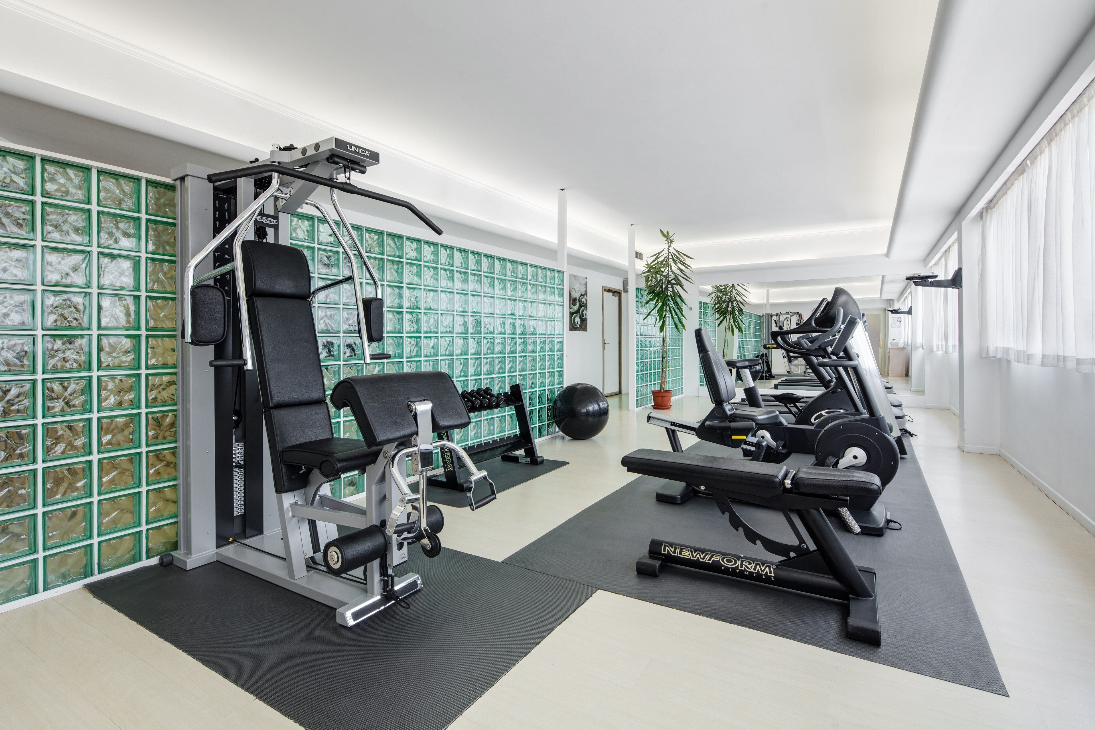 Uma academia moderna com diversos equipamentos de exercícios, incluindo um banco de supino, leg press e máquina de cabo.