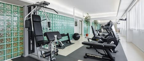 A modern gym with various exercise equipment, including a bench press, leg press, and a cable machine.
