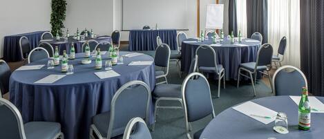A conference room with round tables, chairs, and a projector screen.