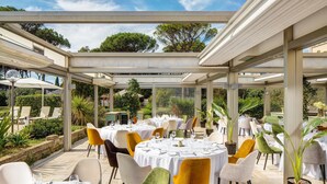 An outdoor dining area with round tables, chairs, and potted plants. - Holiday Inn Rome- Eur Parco Dei Medici by IHG (Rome)