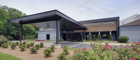 A Courtyard by Marriott hotel with a covered entrance, landscaped garden, and modern architecture.