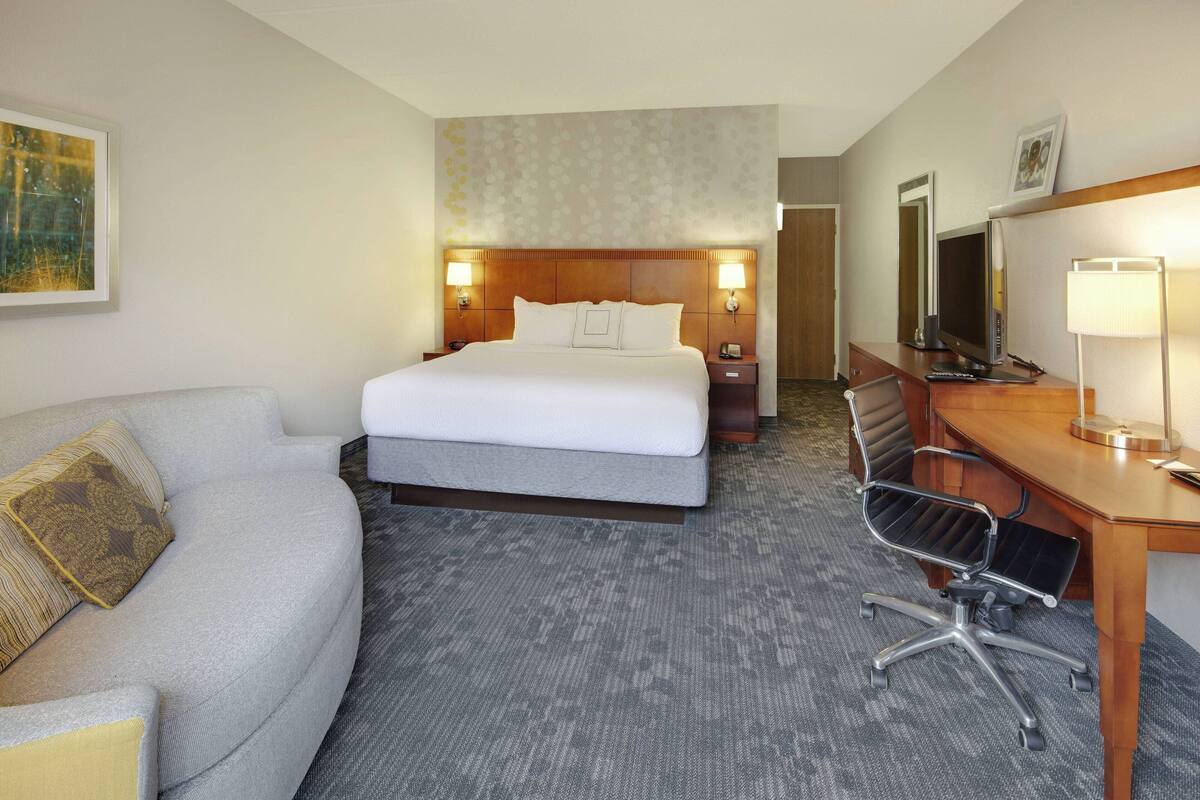 Een hotelkamer met een bed, een bureau met stoel, een bank en een televisie.