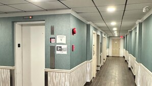 Een hotelgang met blauwgroene wanden, witte details en een rood tapijt.