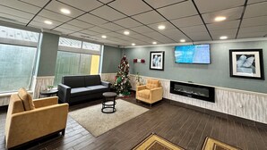 Een moderne woonkamer met een open haard, een kerstboom en een flatscreen televisie aan de muur.