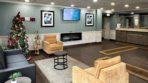 Een moderne lobby met een flatscreen televisie, comfortabele zitplaatsen, een kerstboom en een kitchenette.