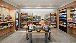Interior de um supermercado, com seções refrigeradas, prateleiras cheias de bebidas, snacks e produtos frescos.