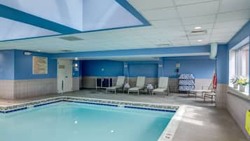 Een binnenzwembad, ligstoelen bij het zwembad