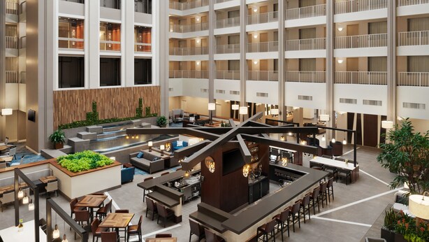 Um hall de hotel espaçoso com várias áreas de refeições, um bar central e uma piscina.