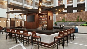 Uma área de bar moderna com uma ilha central, banquetas e diversos tipos de garrafas.