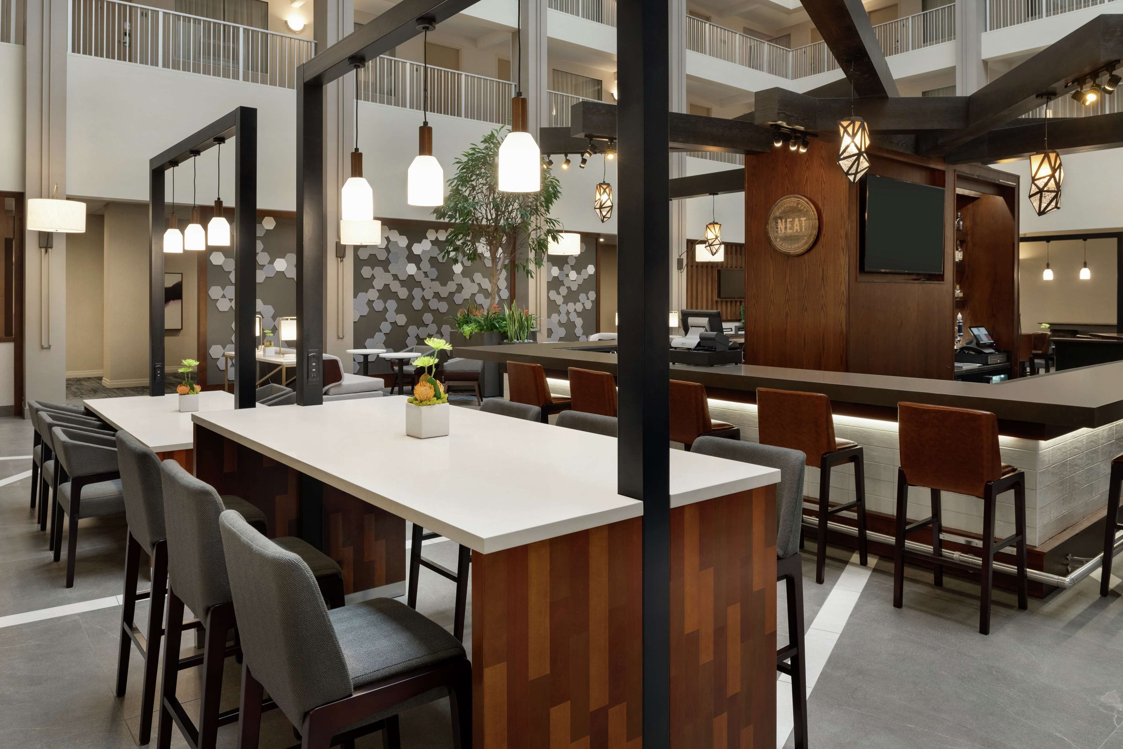 A modern hotel lobby with a long reception desk, multiple seating areas, and a high ceiling with exposed beams.