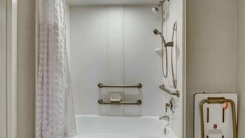 A modern bathroom with a white bathtub, grab bars, a shower with a handheld showerhead, and a towel rack.