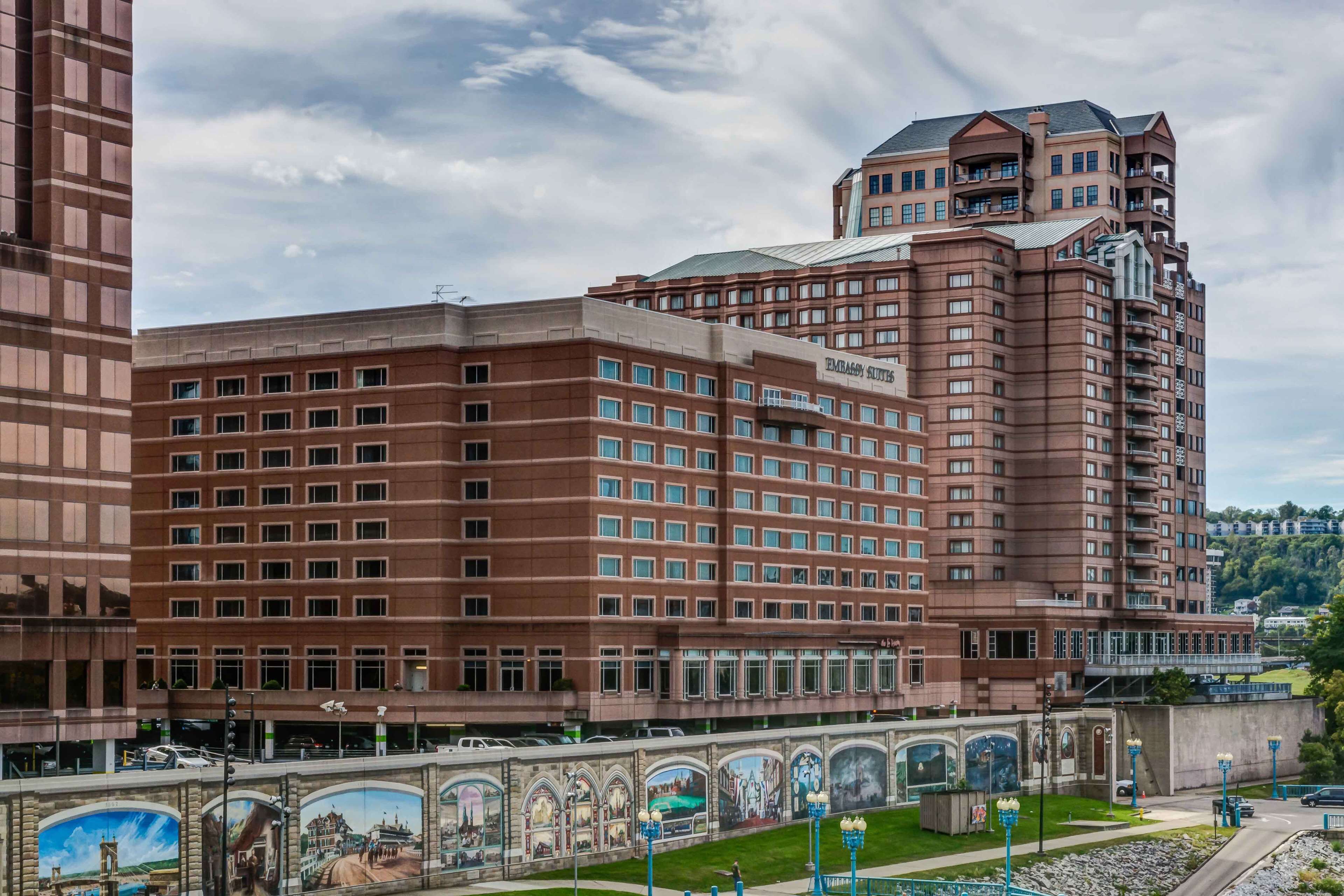 A large hotel with multiple floors, a prominent entrance, and a mural of historical scenes along the walkway.