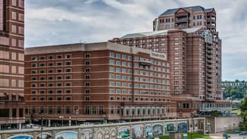 A large hotel with multiple floors, a prominent entrance, and a mural of historical scenes along the walkway.