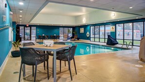 A pool area with a table and chairs, a lifeguard chair, and a pool lift.