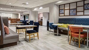 A modern lounge area with seating arrangements, a reception desk, and a patterned wall.