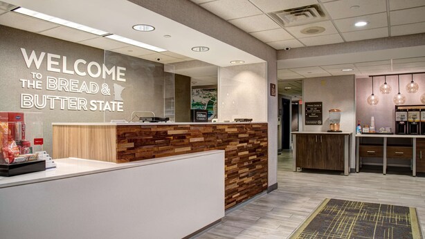 A reception area with a wooden reception desk, a "Welcome to the Bread & Butter State" sign, and a "Please Center" sign.