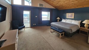 A bedroom with a large bed, a TV, a bench, and a view of the outdoors. - 108 Golf Resort (108 Mile Ranch)