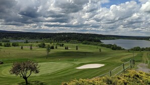 A golf course with a lake, trees, and a cloudy sky. - 108 Golf Resort (108 Mile Ranch)