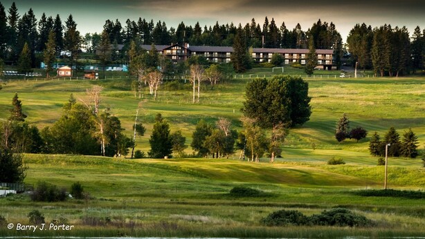 A golf course with a clubhouse and multiple buildings in the background. - 108 Golf Resort (108 Mile Ranch)
